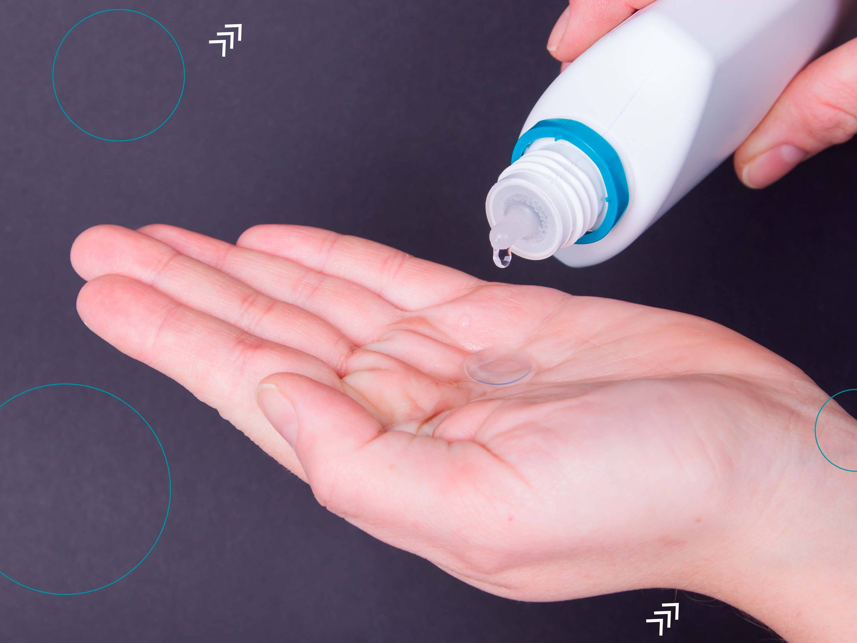 Imagen de una persona que sostiene un lente de contacto sobre la palma de la mano, mientras que le pone solución de mantenimiento para limpiarlo y guardarlo