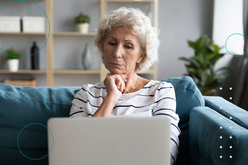 mujer mayor sentada en el sofá viendo el ordenador