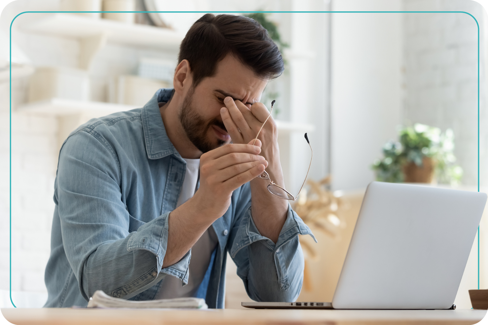 hombre frente a su computadora, quitándose sus lentes 