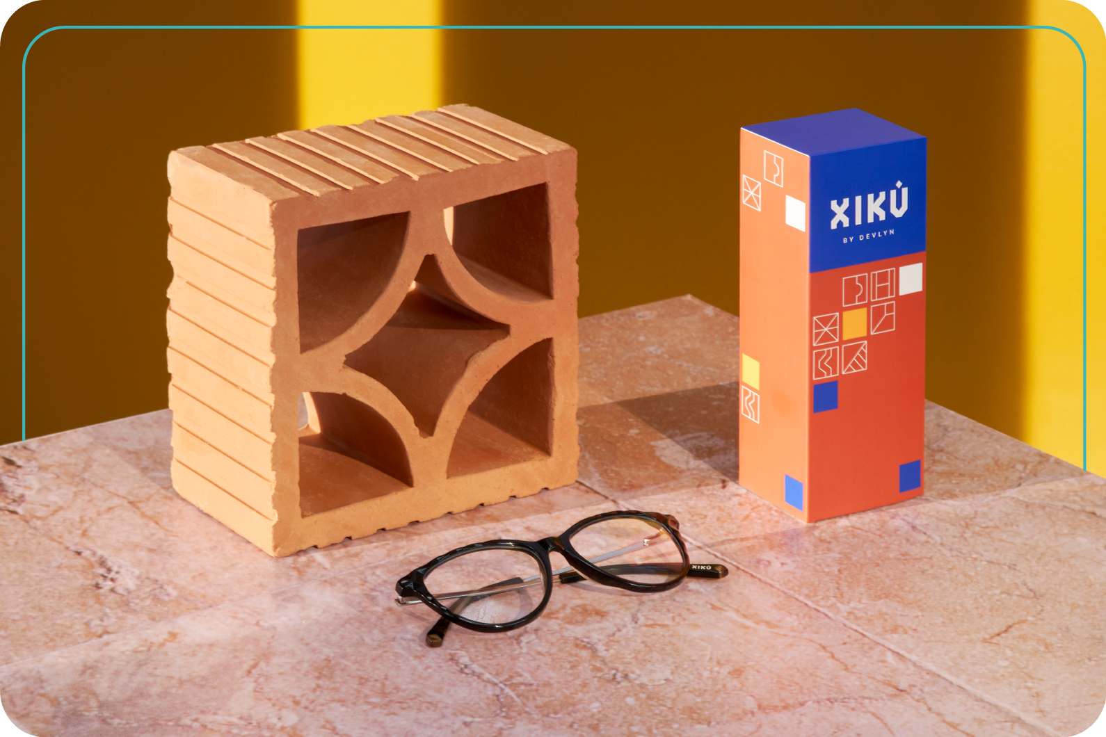 lentes oftálmicos xikú sobre un mosaico, acompañado de un ladrillo y el empaque de lentes oftálmicos xikú