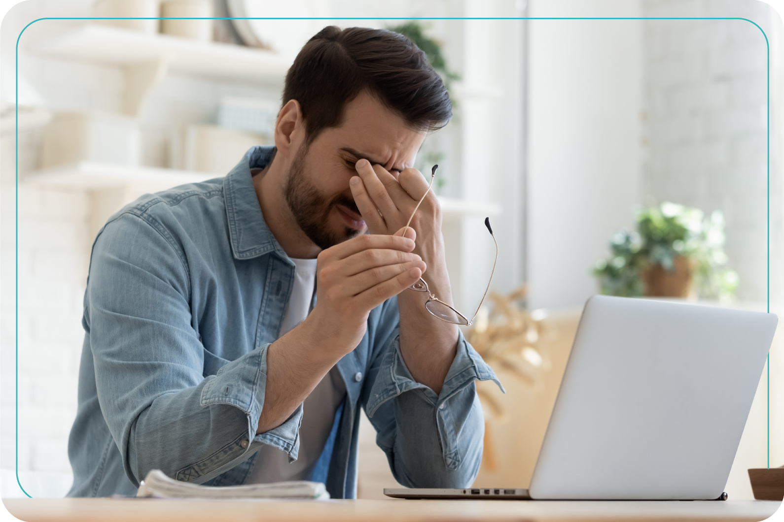Hombre sentado en su escritorio con notable cansancio ocular, se masajea los ojos y tiene los lentes en su mano