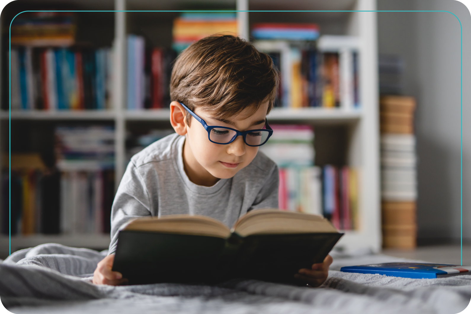 niño leyendo un libro en su cuarto usando lentes
