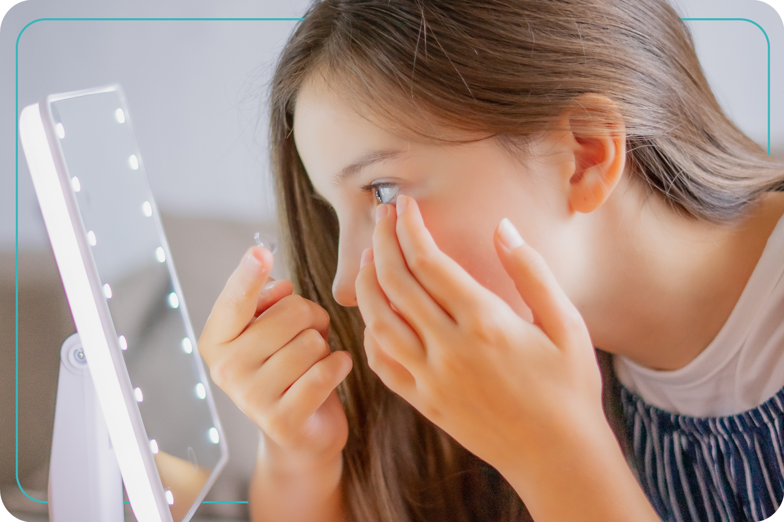 adolescente colocando lentes de contacto frente a un espejo iluminado