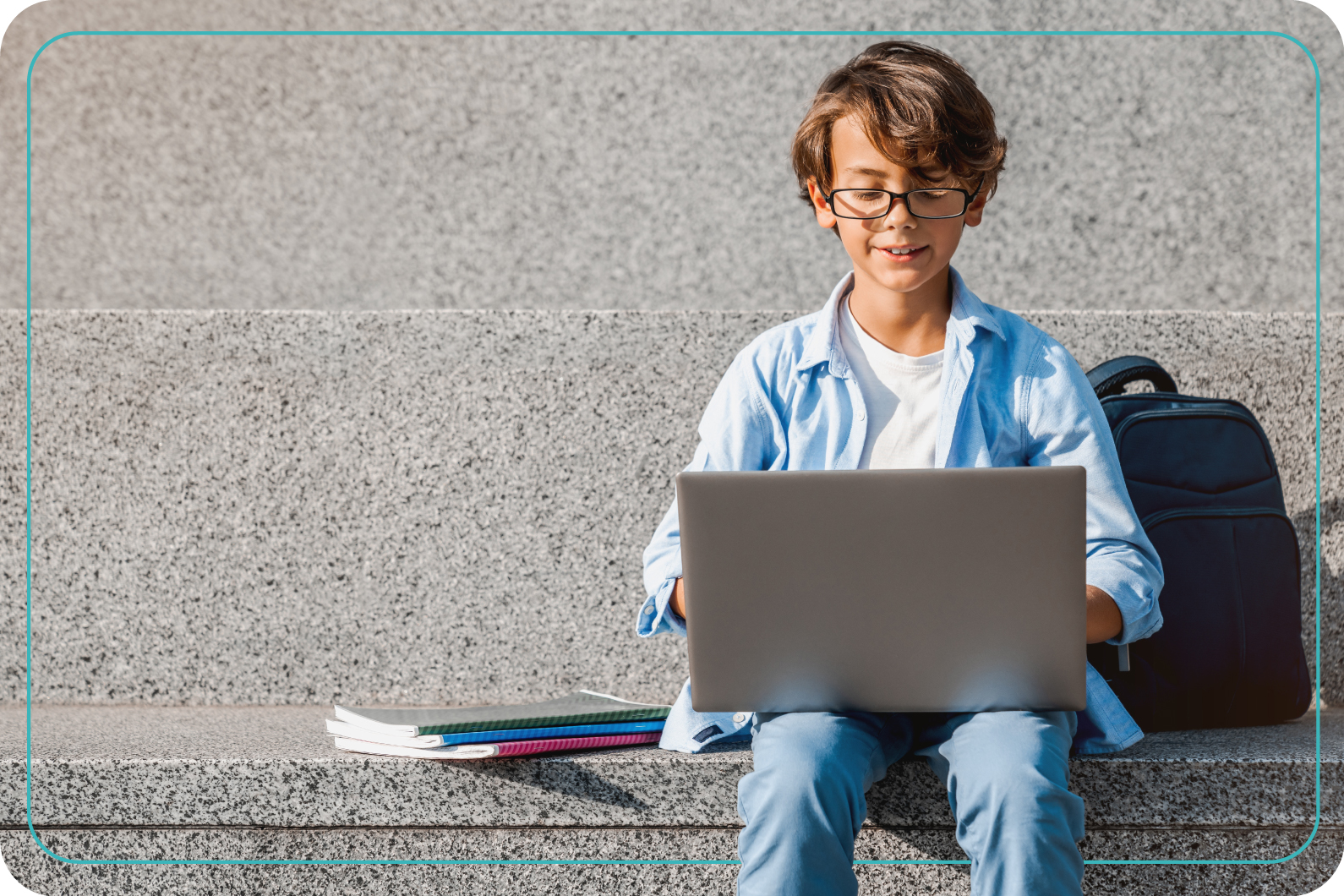 Niño castaño, sentado con una computadora usando lentes oftálmicos con antireflejante